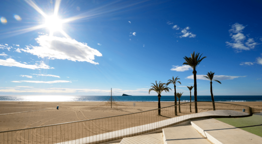 A sunny day at Poniente Beach in Benidorm with clear skies and calm waters.