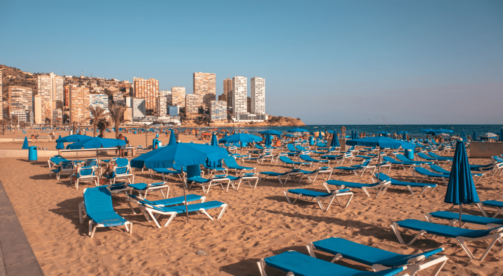 Sunbeds lined up on Levante Beach in Benidorm, basking under a bright, sunny sky.