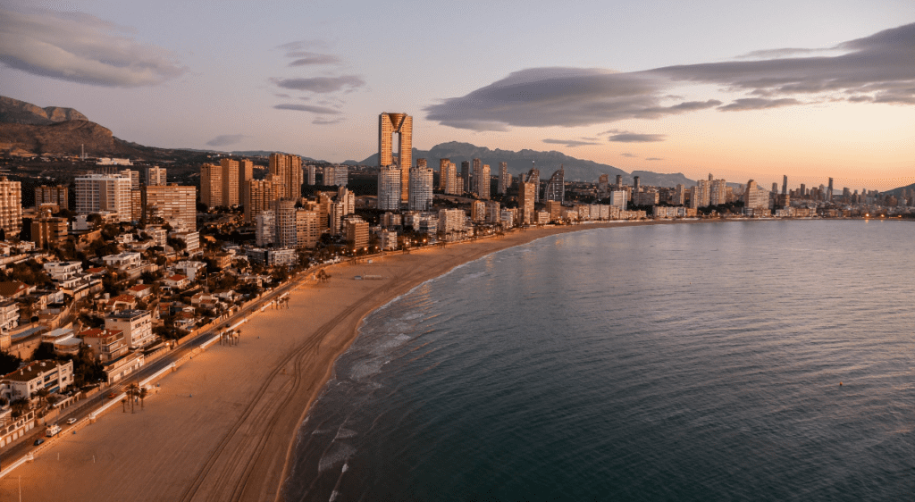 A panoramic view of Benidorm’s skyline and Poniente Beach at sunset with the Intempo building standing tall.