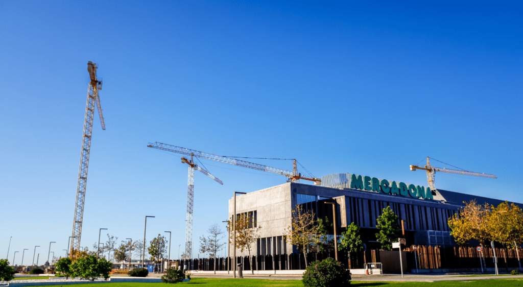 Exterior of a Mercadona supermarket under construction with cranes in the background 